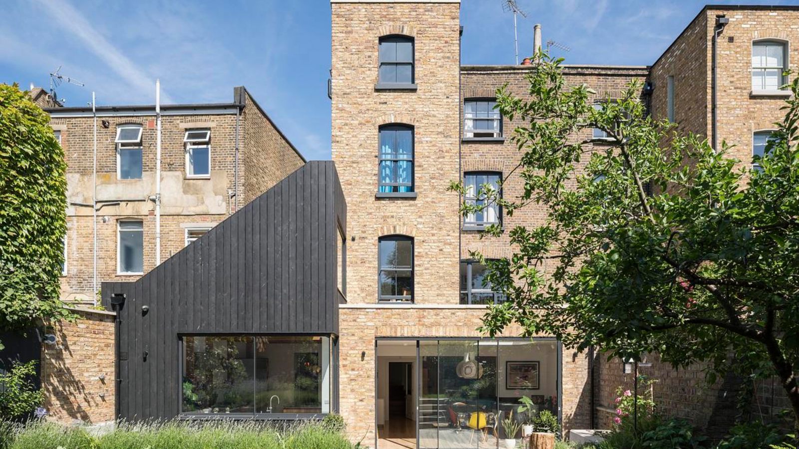 large brick victorian semi detached property with black clad angular extension to one side and brick rear extension next to it