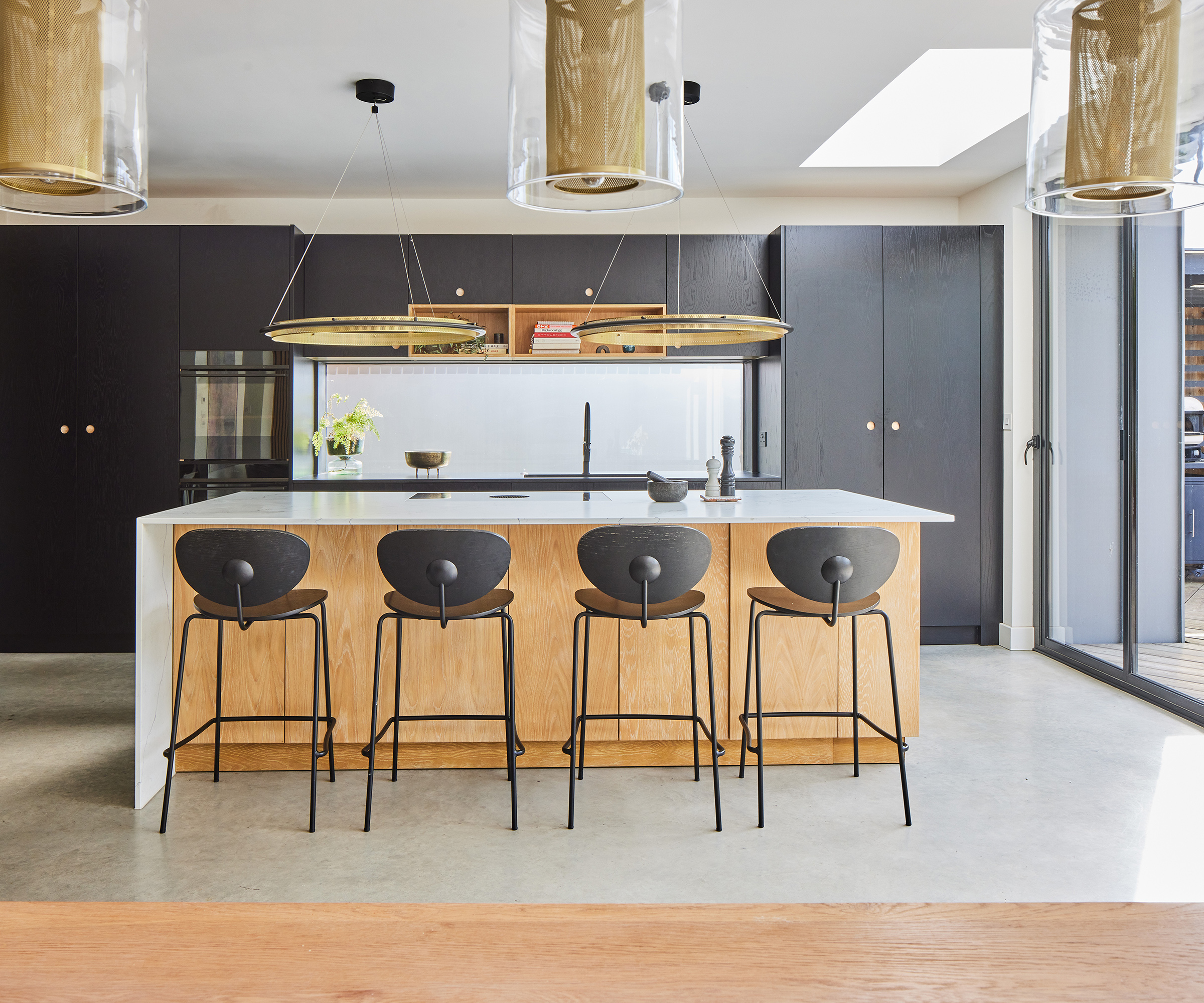 A contemporary kitchen with large island with bar stools and hanging pendant lights