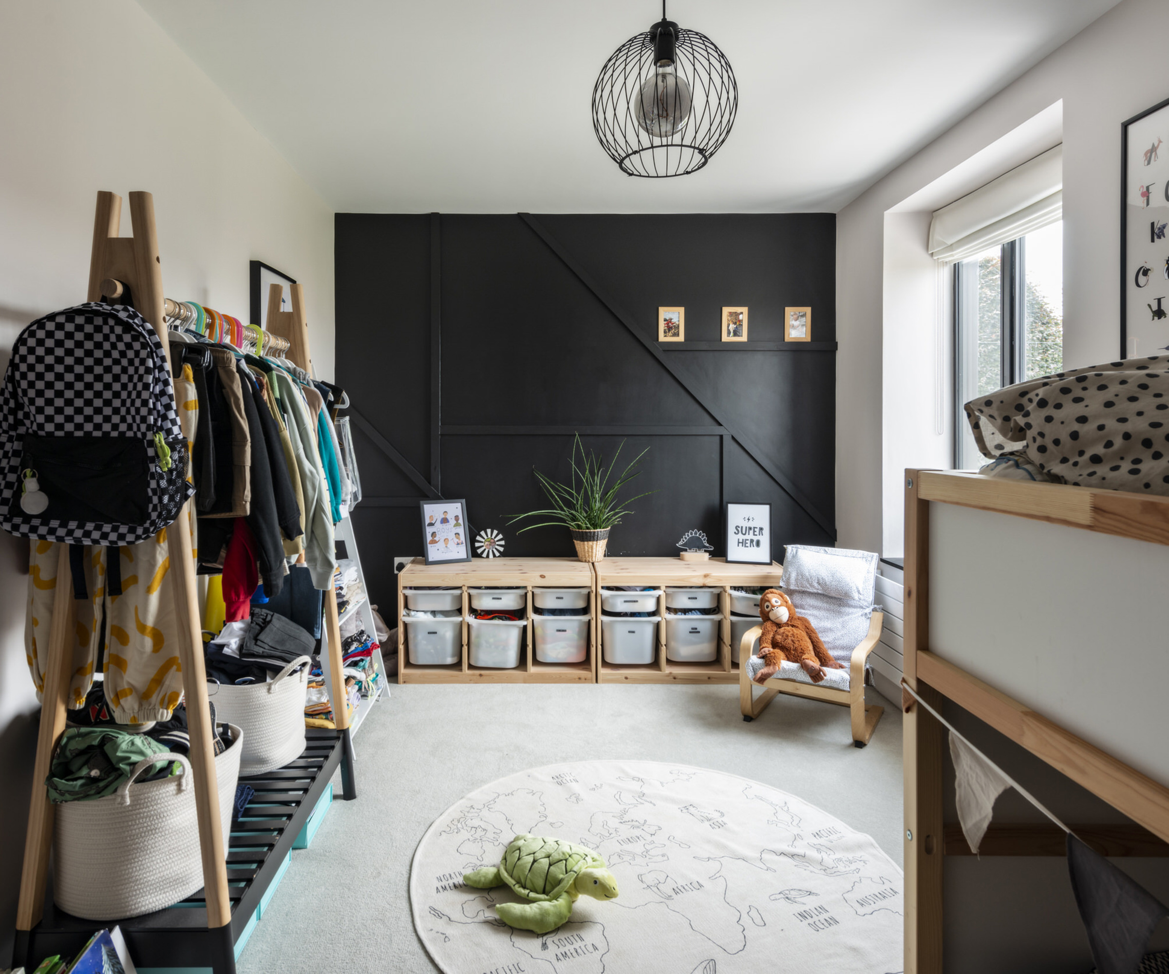 A child's bedroom with wooden storage and clothes rack and circular rug on the floor