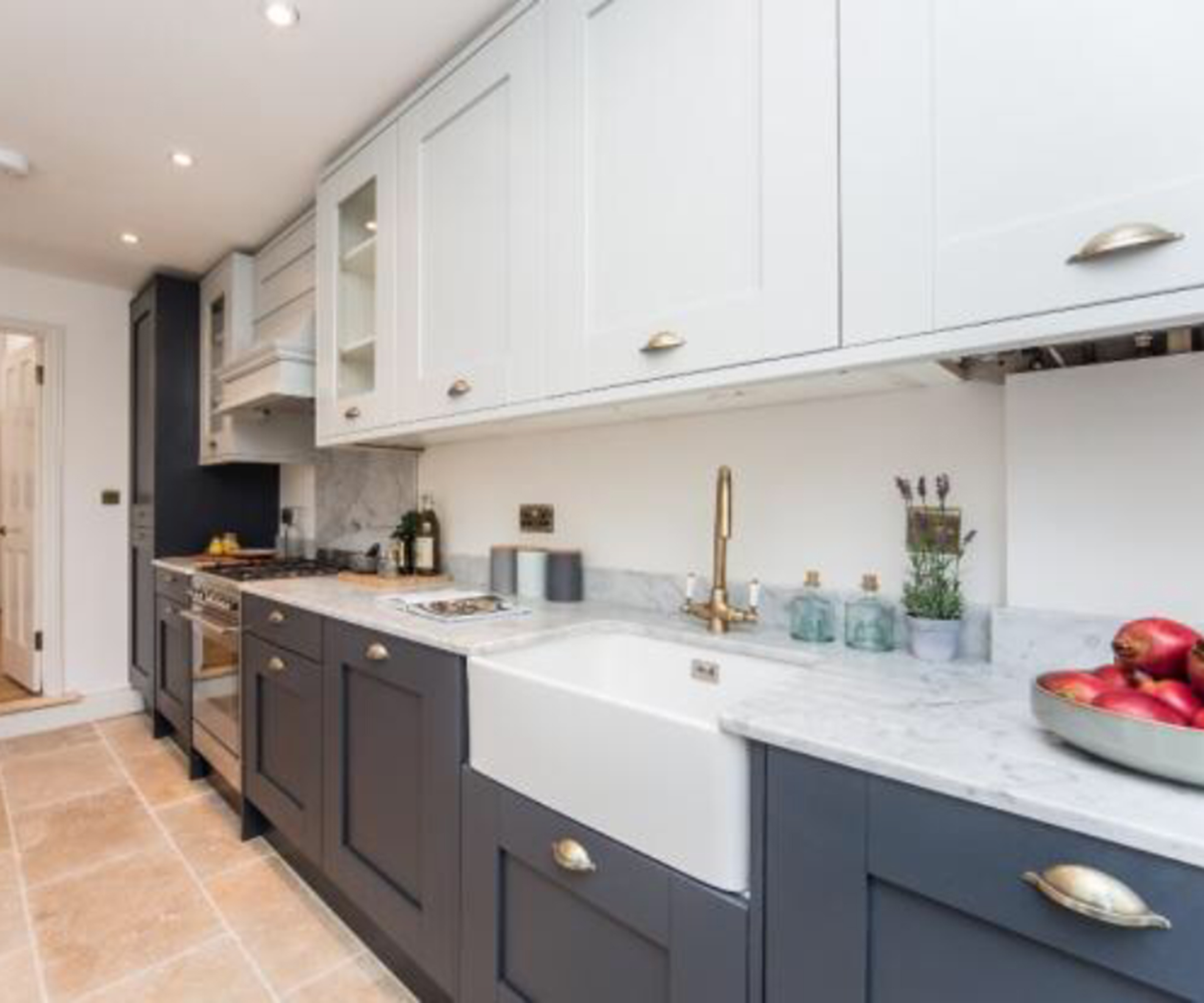 A galley kitchen with light counter tops and overhead cupboards and contrasting dark on the bottom cabinets