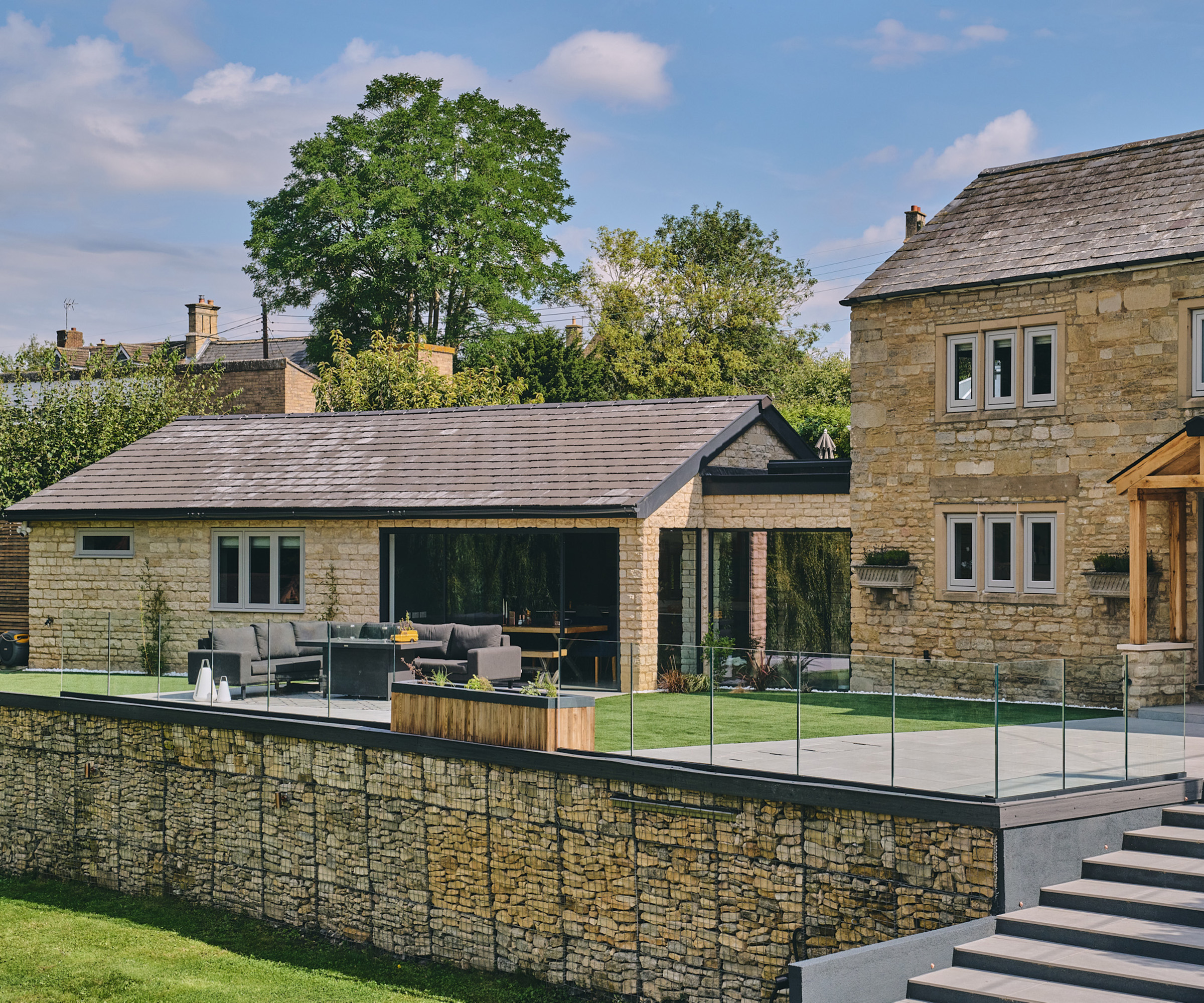 A contemporary stone extension attached to a stone cottage with an adjoining bridge corridor